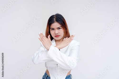 A serious and unimpressed young woman doing an x-sign with her arms. Isolated on a white background.