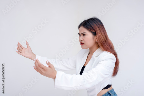 An angry and frowning young woman extending both of her arms wide open in frustration. Isolated on a white background.