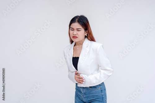 A distressed young woman with stomach ache holding her stomach in pain. Isolated on a white background.