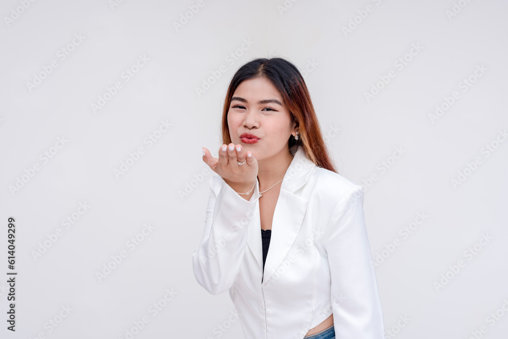 A happy and charming young woman blowing a kiss while facing the camera. Isolated on a white background. A happy and charming young woman blowing a kiss while facing the camera. Isolated on a white background.
