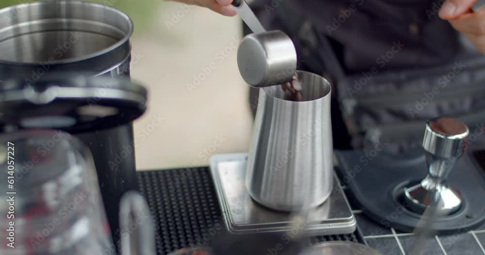 Coffee beans are weighed before grinding to get just the right amount of flavor.Male hands weighing coffee beans in stainless steel mug.Coffee shop for passers-by.Drink coffee for health. Coffee beans are weighed before grinding to get just the right amount of flavor.Male hands weighing coffee beans in stainless steel mug.Coffee shop for passers-by.Drink coffee for health.