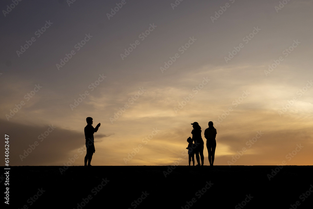 Silhouettes of people on the beach at sunrise