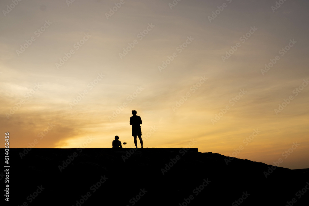 Silhouettes of people on the beach at sunrise