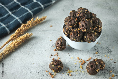 Kue coklat or Chocolate cookies or choco button cookies for Lebaran. Made from butter, egg, dark cooking chocolate, flour, cocoa pwder and cashew nut. served in grey and texture background photo