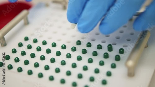 Crop pharmacist putting capsules into filling machine in lab