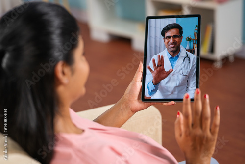 Shoulder shot of indian pregnant woman consulting doctor on video call at home - concept telemedicine, Virtual healthcare and remote consultation.