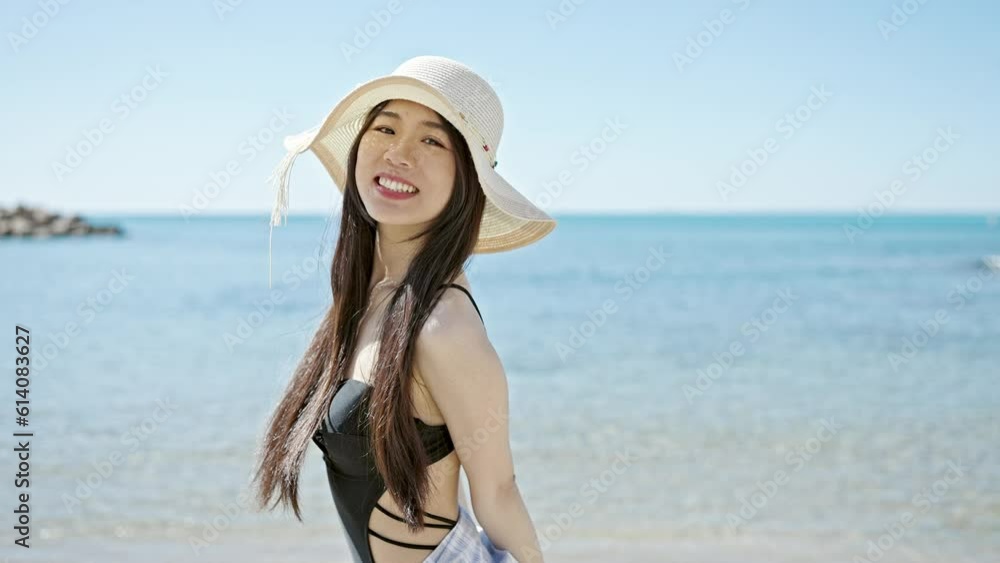 Young chinese woman tourist wearing swimsuit doing come gesture with hand at seaside Young chinese woman tourist wearing swimsuit doing come gesture with hand at seaside
