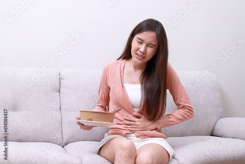 Bilde på lerret Asian woman sitting on the sofa having diarrhea from the food she eats