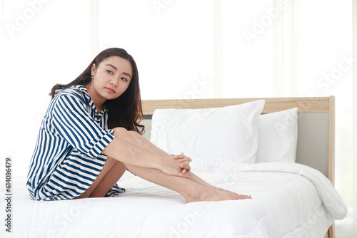 Beautiful Asian woman sitting on the bed in the bedroom. health care concept. copy space