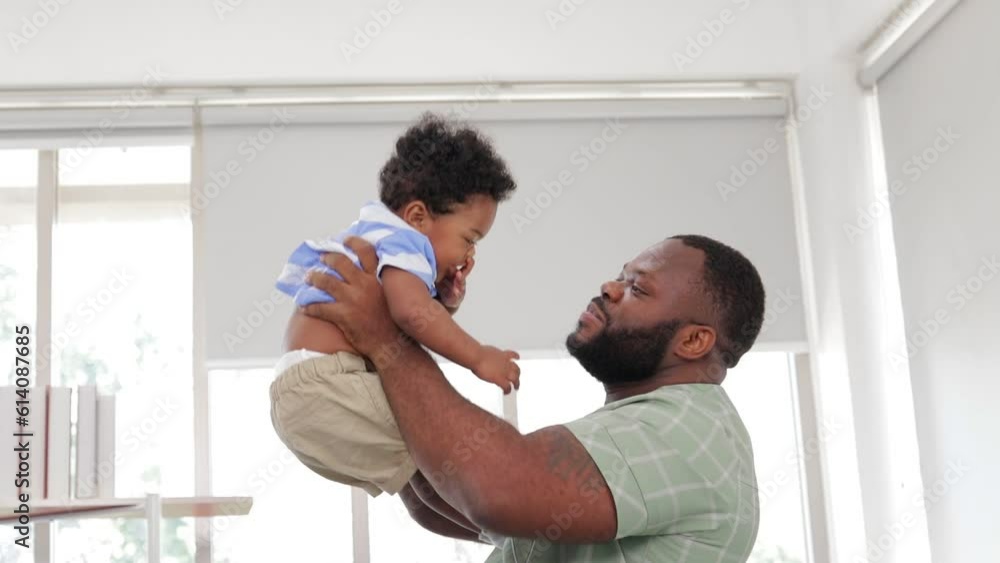 father and little son playing together They smile happily in their living room at home. African American family at home father and little son playing together They smile happily in their living room at home. African American family at home