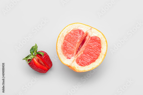 Half of grapefruit with strawberry on light background. Sex concept