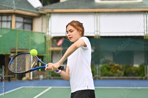 Shot of young female athlete hitting tennis ball flying towards her. Sport, training, competition and active life concept © Prathankarnpap