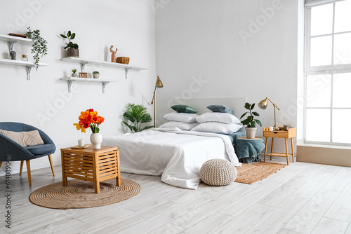 Interior of stylish bedroom with tulip flowers in vase on wooden table