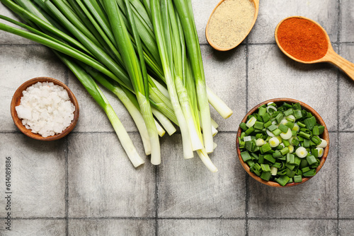 Fresh green onion and spices on dark tile background