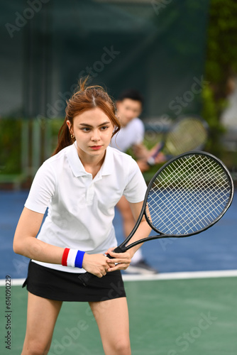 Focused female athlete with a racket waiting to receive ball during match. Sport, training and active life concept © Prathankarnpap