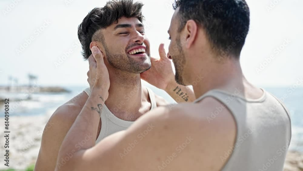 Two men couple smiling confident hugging each other and kissing at seaside Two men couple smiling confident hugging each other and kissing at seaside