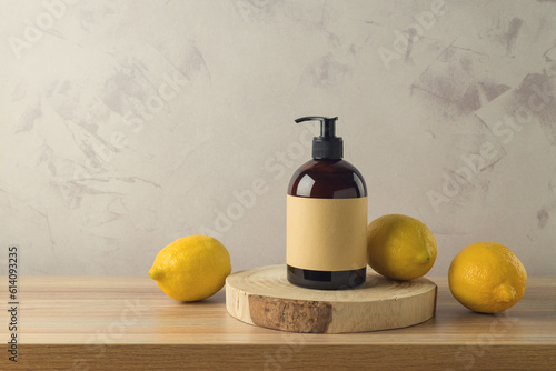 Shampoo or shower gel  bottle with extract of lemon on wooden table. Mock up packaging design background