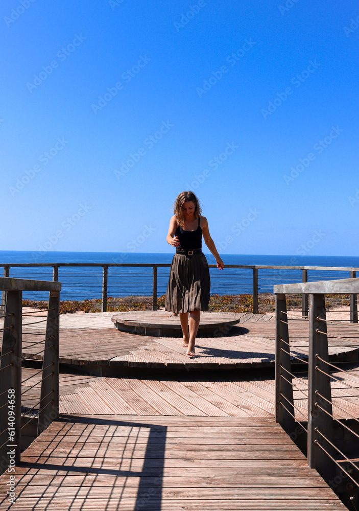 A female traveler running gracefully towards camera. Front view of a girl running with the horizon and the ocean in the background.