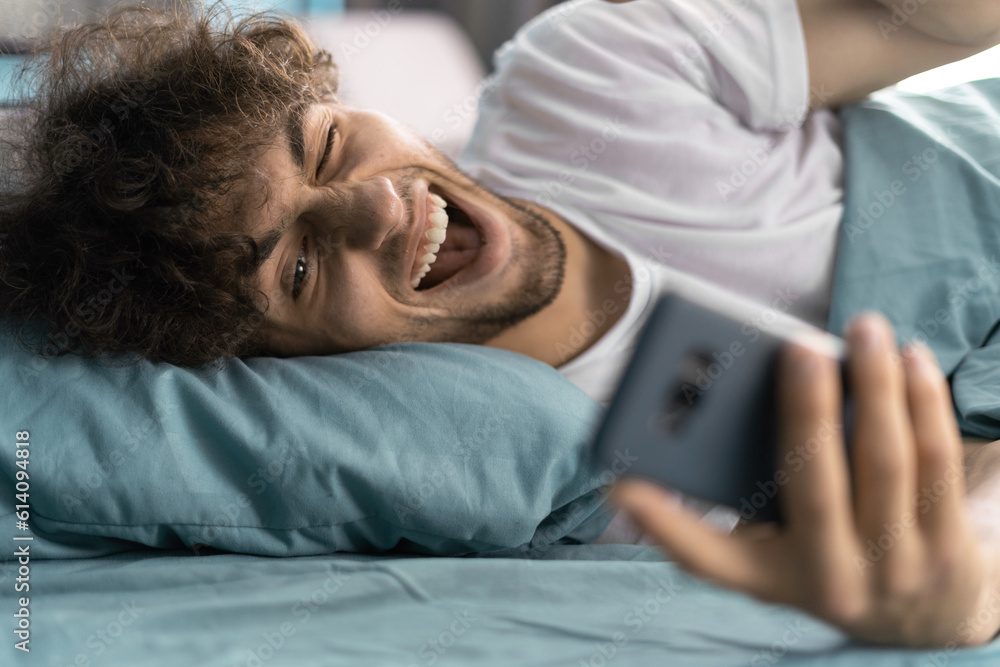 Happy arabic man video calling a girlfriend on a smartphone on the bed after waking up in the morning Happy arabic man video calling a girlfriend on a smartphone on the bed after waking up in the morning