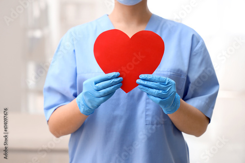 Fototapeta Naklejka Na Ścianę i Meble -  Female nurse with paper heart in clinic, closeup