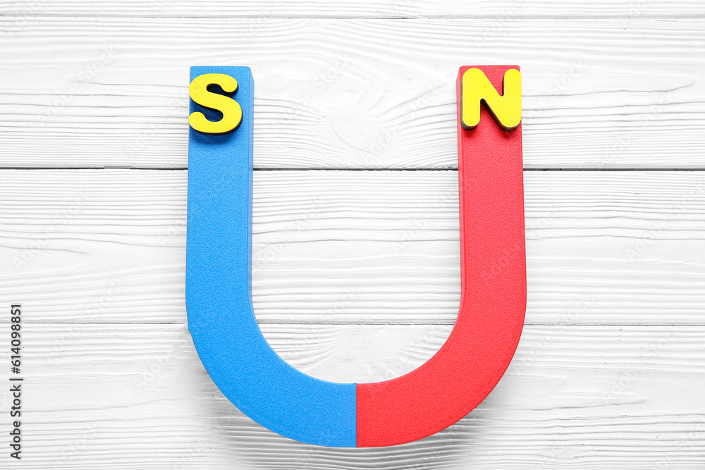 Horseshoe shaped magnet with North and South poles on white wooden background Horseshoe shaped magnet with North and South poles on white wooden background