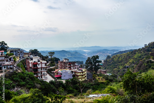 high angle shot of houses along side mountains and cloudy sky in the background © winistudios