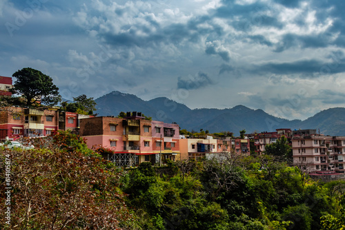 low angle shot of small town along side trees with mountains and cloudy blue sky in the background © winistudios