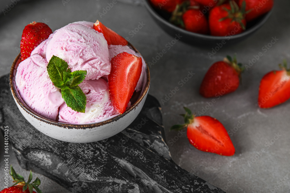 Bowl of delicious ice cream scoops with fresh strawberries and mint on grey grunge table Bowl of delicious ice cream scoops with fresh strawberries and mint on grey grunge table