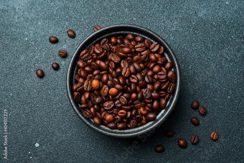 Roasted Arabica or Robusta coffee beans in a black bowl. Macro photo. Coffee background.