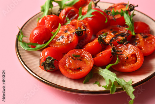 Plate with tasty grilled tomatoes and arugula on pink background