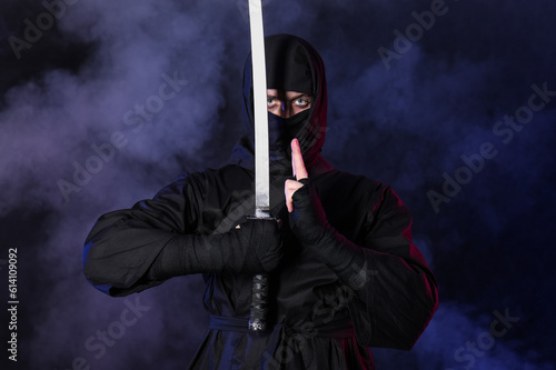 Male ninja with sword on dark background