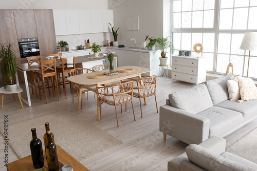 Interior of light open plan kitchen with dining table  island and grey sofa