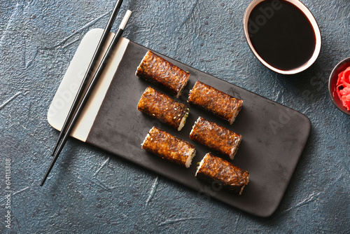 Tasty maki rolls, soy sauce and chopsticks on dark background