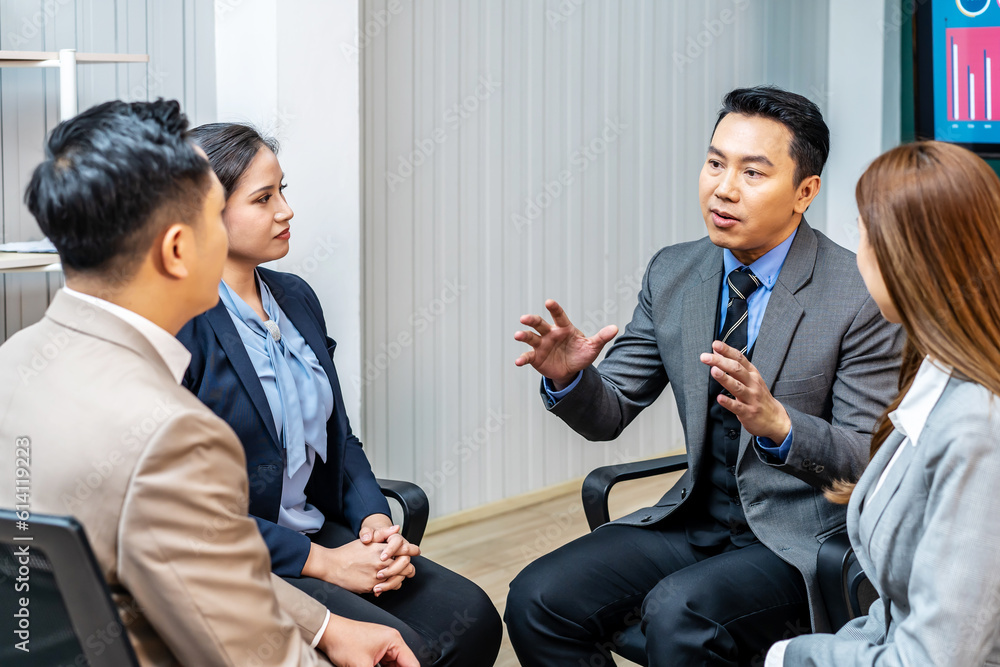 Happy group leader asian man speaking on team building meeting. Business team sitting on chairs in circle use tablet, talking, discussing project ideas, brainstorming, listening to male boss Happy group leader asian man speaking on team building meeting. Business team sitting on chairs in circle use tablet, talking, discussing project ideas, brainstorming, listening to male boss