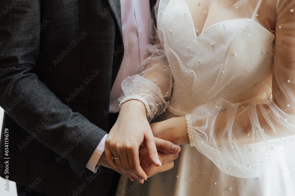 The young wedding couple in love hold of hands. Close-up of hands.