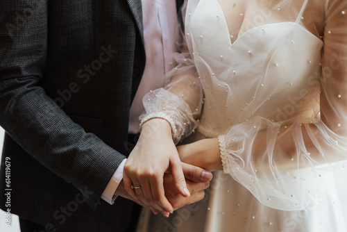 Obraz na płótnie The young wedding couple in love hold of hands. Close-up of hands. w salonie
