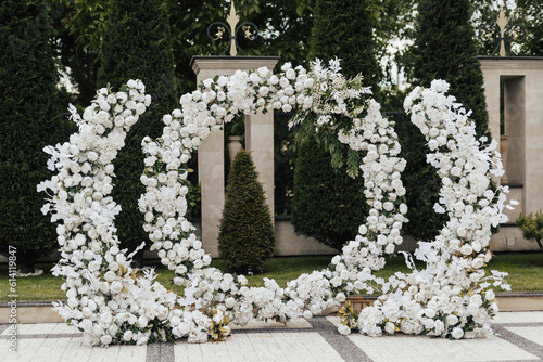 Obraz na płótnie Beautiful wedding round arch decorated with white flowers and greenery in the green garden. Wedding ceremony outdoor. w salonie