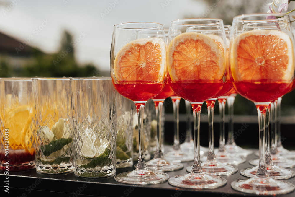Set of alcoholic cocktails in glasses on the black table at outdoor party.