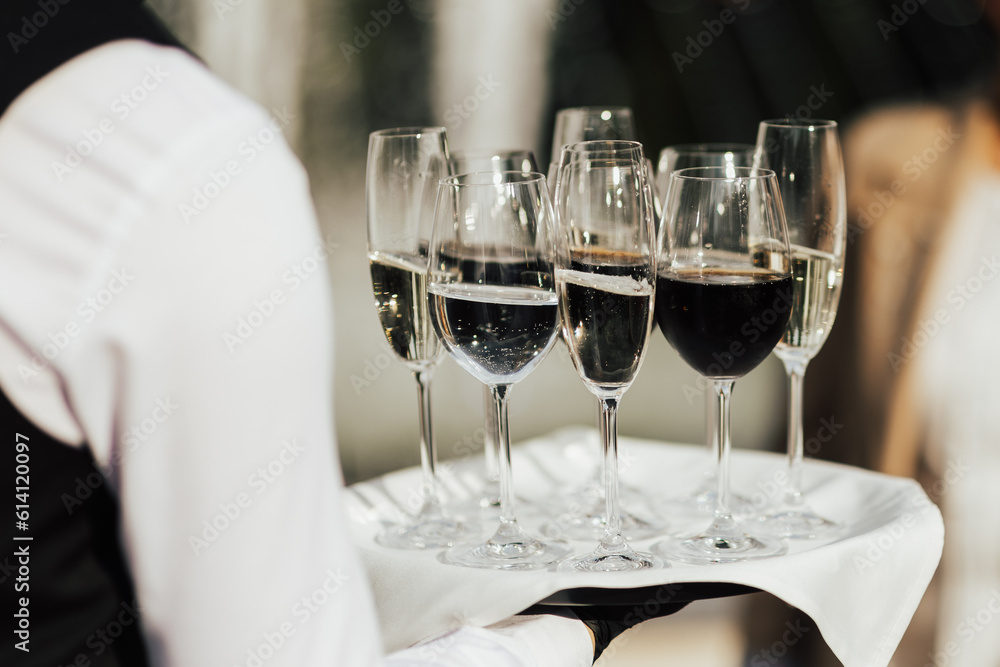 Waiter hold tray with glasses of champagne and wine. Waiter holding a serving tray full of drinks in glasses.