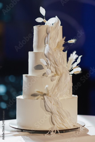 Beautiful white four-tiered wedding cake decorated with white flowers. Wedding cake.