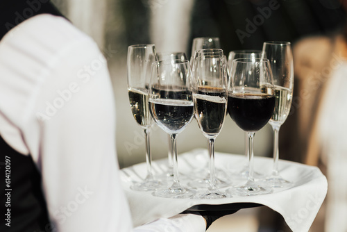 Obraz na płótnie Waiter hold tray with glasses of champagne and wine. Waiter holding a serving tray full of drinks in glasses. w salonie