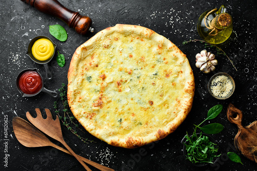 Classic four cheese pizza. Cheese pizza. On a black stone background. Top view. photo