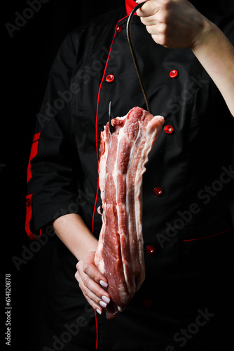 A piece of pork belly meat. The chef prepares bacon porchetta. On a black background.
