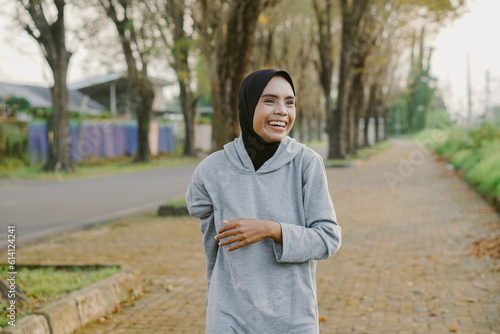 asian muslim woman running and exercising outdoors excitedly