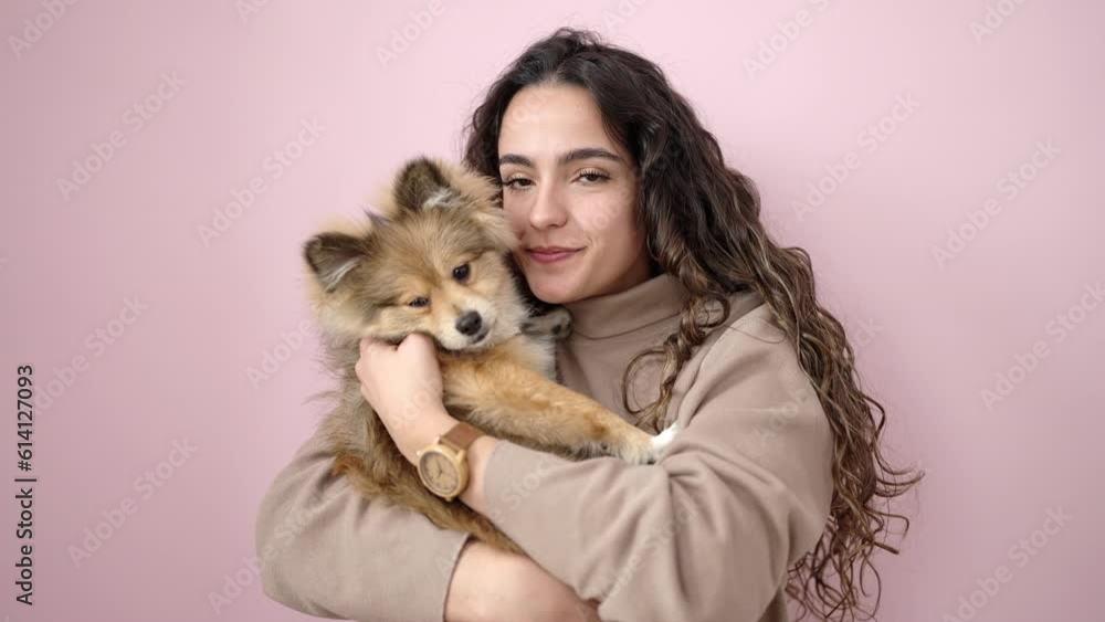Young hispanic woman with dog smiling confident standing over isolated pink background Young hispanic woman with dog smiling confident standing over isolated pink background