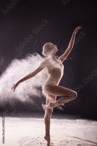 Ballerina on a black background with a cloud of white flour.