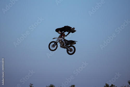FMX rider performs dangerous stunts at sunset. Motocross.