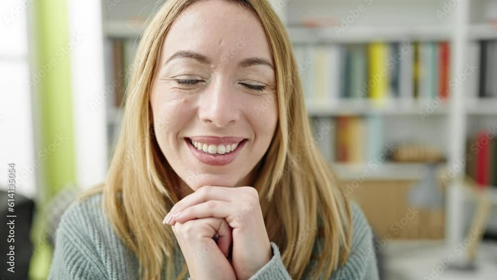 Young blonde woman student sitting on table smiling at library university Young blonde woman student sitting on table smiling at library university