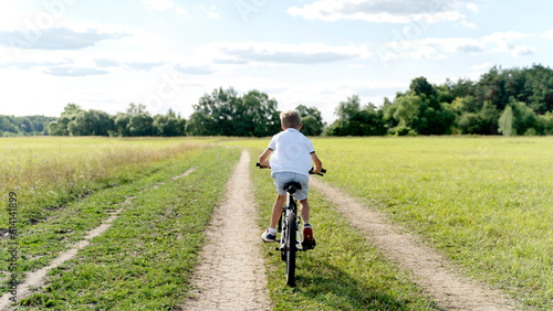 a boy rides a bicycle in nature © I