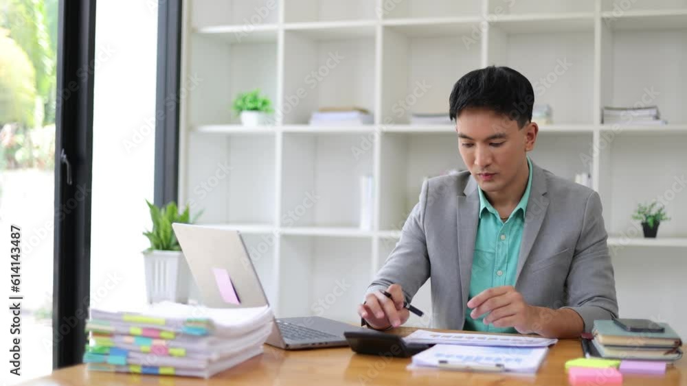 Serious businessman working on paperwork on laptop and financial accounting documents with calculator on office desk. Serious businessman working on paperwork on laptop and financial accounting documents with calculator on office desk.